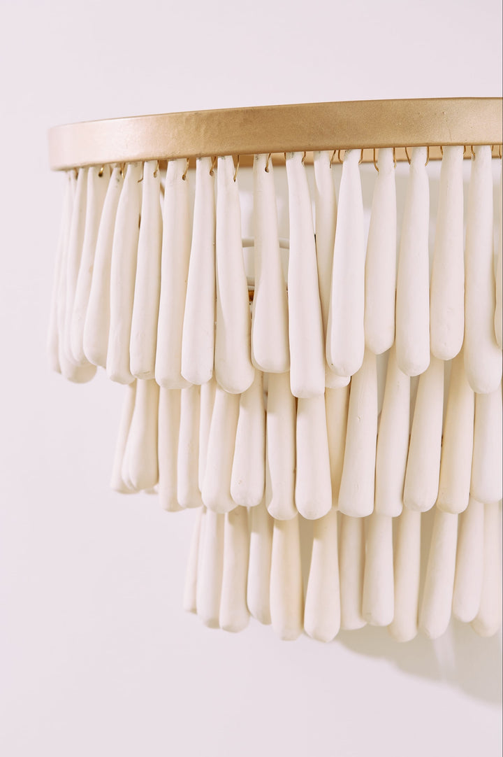 Decorative wall piece with white cylindrical elements and gold base on a light background