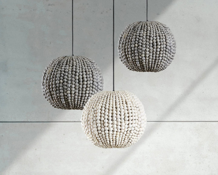 Three spherical pendant lights hanging against a concrete wall.