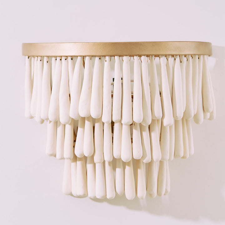 Decorative wall light fixture with white beads and gold base on a white background